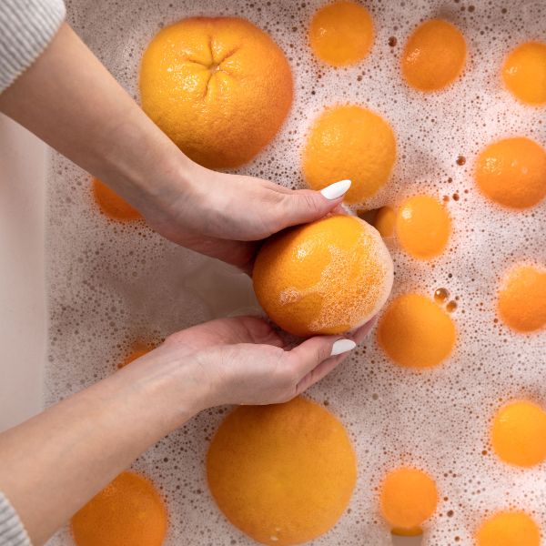 Hand washing oranges in soapy water